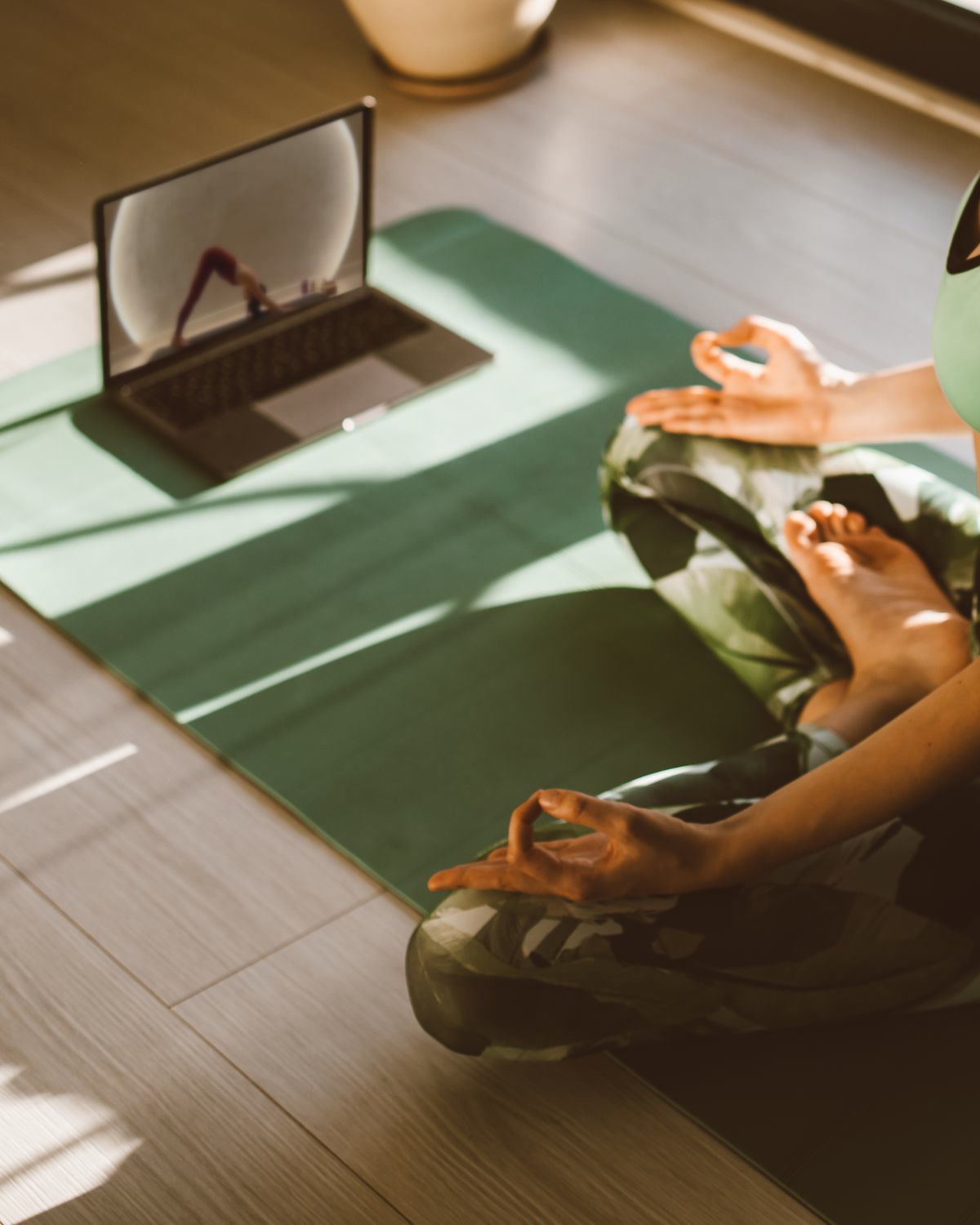 Aluna meditando em casa diante de um notebook com a aula da Letícia